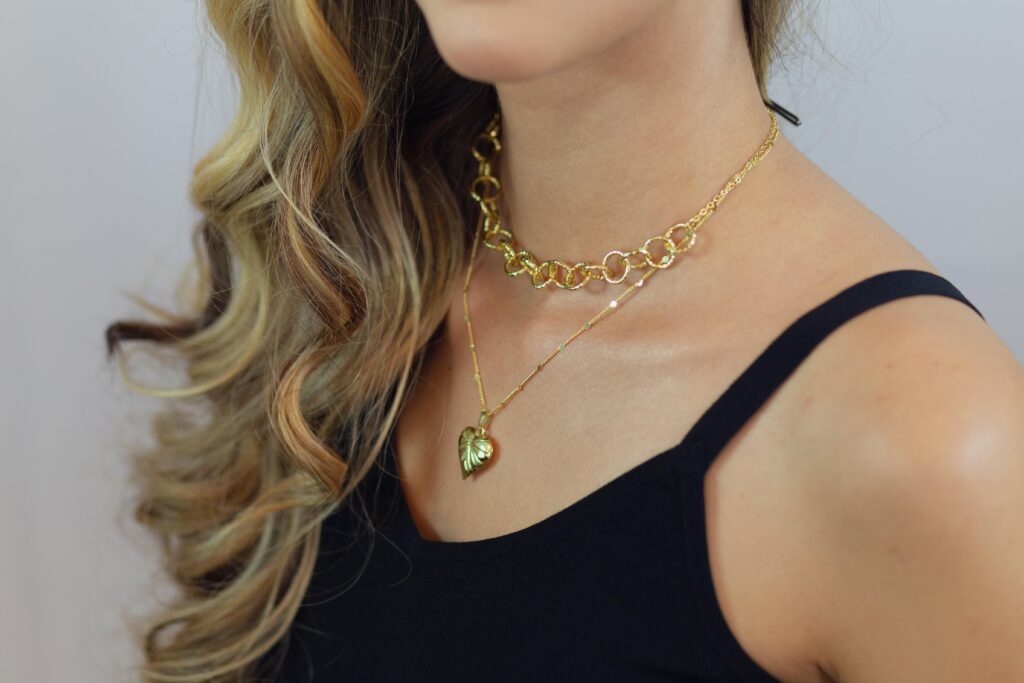 Close-up portrait of a woman with elegant gold jewelry and wavy hair, displaying style and sophistication.