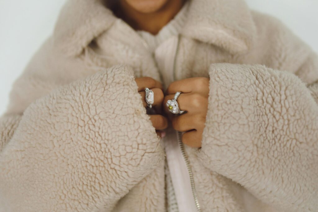 Close-up of hands in a fluffy faux fur coat adorned with stylish rings.